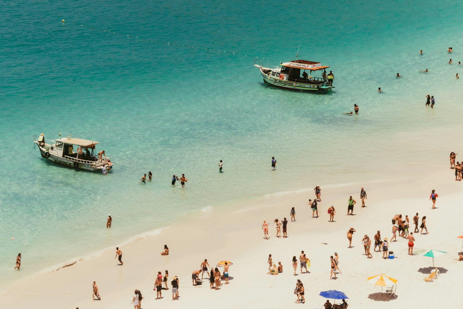 Boats and people enjoying a sunny day at the beach.