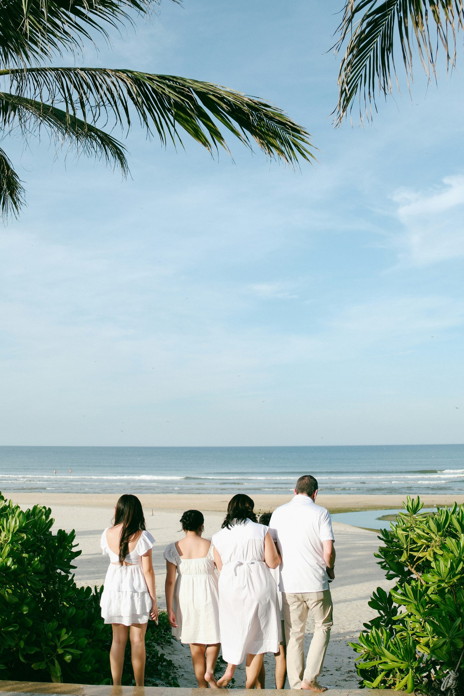 Family in white clothing looking at the ocean